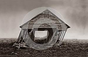 An aged barn leans and nears collapse in this vintage sepia photograph photo