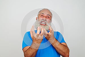 Aged bearded man grimacing at the camera expressing extreme nervousness photo