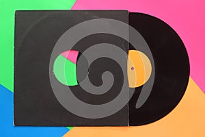 Aged black paper cover and black vinyl LP record isolated on colorful background