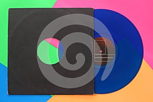 Aged black paper cover and blue vinyl LP record isolated on colorful background
