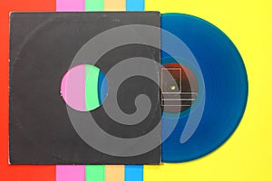 Aged black paper cover and blue vinyl LP record isolated on colorful background