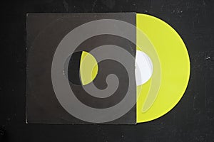 Aged black paper cover and yellow vinyl LP record isolated on dark background