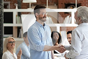 Aged boss welcoming new employee with handshake symbol of respect