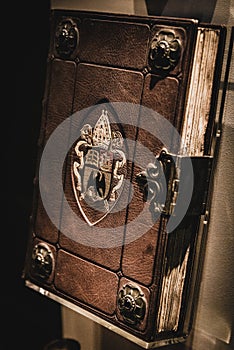 Aged brown leather book with embossed symbols of an eagle, a ship, a book and pope`s hat and lock.