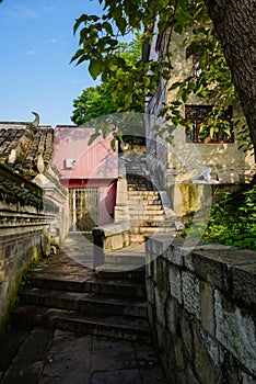Aged buildings by stone stairway on slope in sunny spring morning