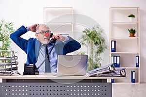 Old businessman clown working in the office