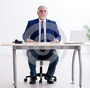 Aged businessman doing yoga exercises in the office