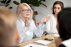 Aged businesswoman, teacher or business coach speaking to young photo