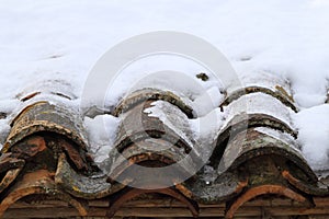 Aged clay roof tiles snowed under winter snow photo