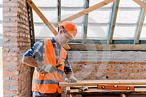 Aged constructor holding hammer near hobnail