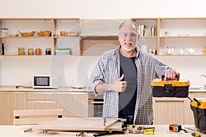 The aged contractor repairman working in the kitchen
