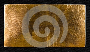 Aged copper plate on black cloth, old worn metal background.