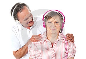 Aged couple enjoying music over white background