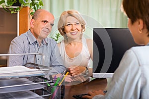 Aged couple of pensioners talking with employee