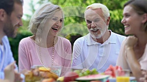 Aged couple on picnic with children, hugging smiling at camera, sweet memories