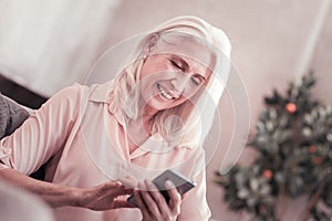 Aged cute lady messaging and smiling.