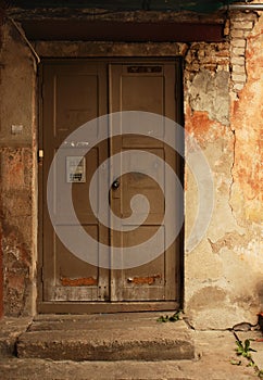 Aged dark wooden door in weathered dirty brick wall