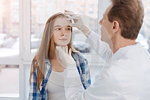 Aged dermatologist touching patient face in the clinic