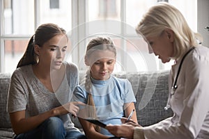 Aged doctor holding clipboard filling little patient information form