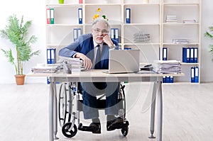 Aged employee in wheelchair working in the office