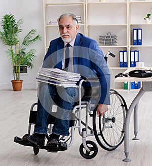 Aged employee in wheelchair working in the office