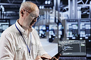 Aged engineer coding in data center