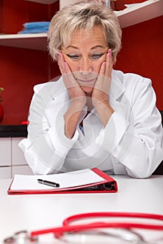 Aged female doctor, in front a plastic brain