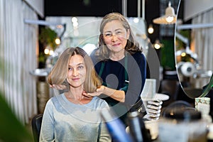 Aged female hairdresser offering modern hairstyling to young woman