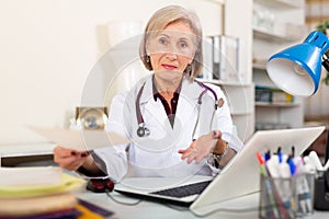 Aged female therapist handing out paper with prescriptions