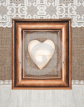 Aged frame with wooden heart on the burlap