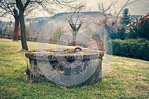 Aged Garden Water Well Covered by Lichen and Moss