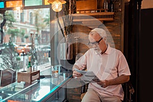Aged grey-haired man reading news in the pub