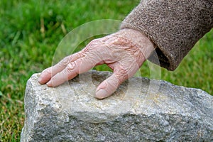 Aged Hand Touching Stone