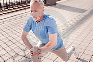 Aged handsome man stretching legs relying on the knee.