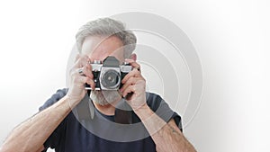 Aged handsome photographer taking a picture with film camera - white background