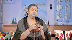 An aged Hindu woman chanting hymns / Mantras - religious faith concept