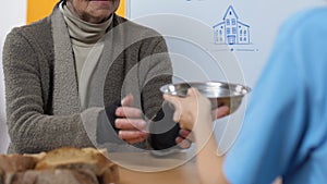 Aged homeless woman accepting food in volunteer center, social insecurity, aid