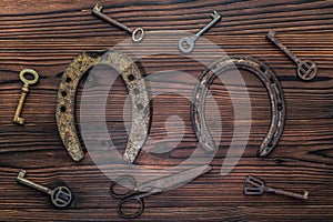aged horseshoes, keys, scissors on wooden background