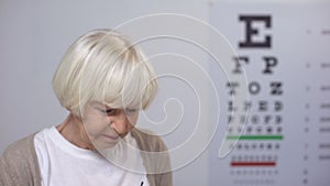 Aged lady putting on glasses, smiling and reading from tablet, focusing vision