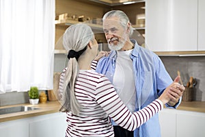 Aged Love. Portrait Of Romantic Elderly Spouses Dancing In Kitchen Interior