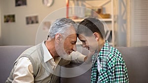 Aged male and boy touching foreheads, friendship between grandpa and grandson