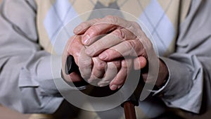 Aged male hands holding walking stick, social pension reform, health care