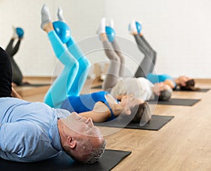 Aged man exercising with pilates ball during group training