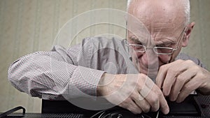 Aged man in glasses unscrews black cower with screwdriver