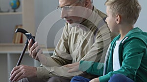 Aged man and grandchild watching video on smartphone together, family closeness