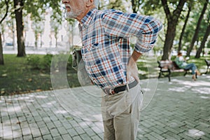 Aged man having backache outdoors stock photo
