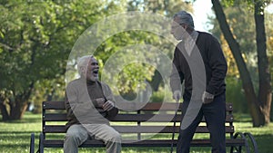 Aged man joking with friend kicking butt, friendship humor, having fun, leisure
