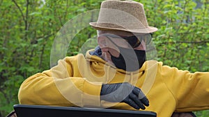 Aged man in mask takes pullovers comparing with online shop