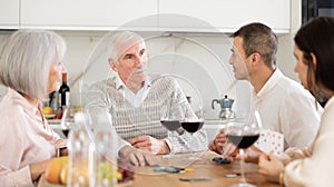 Aged man participating family poker night in cozy kitchen