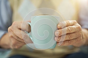Aged man resting at home with a cup of hot drink
